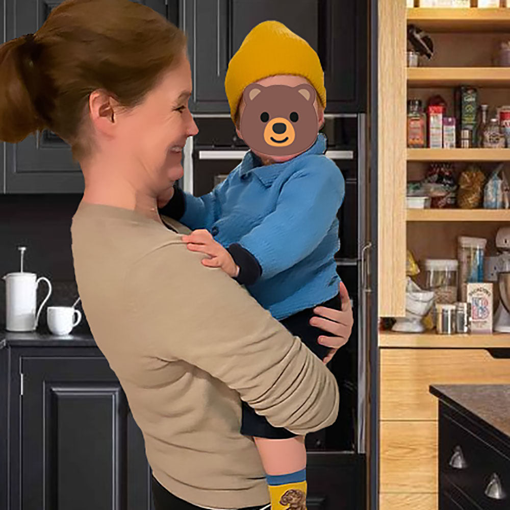 Co-founder Morag holding her little boy standing in a kitchen